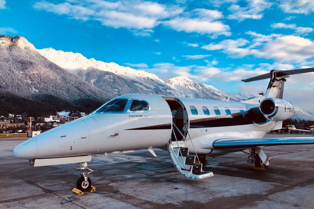 Jet Phenom 300 de Pan Européenne Air Service sur le tarmac devant les montagnes